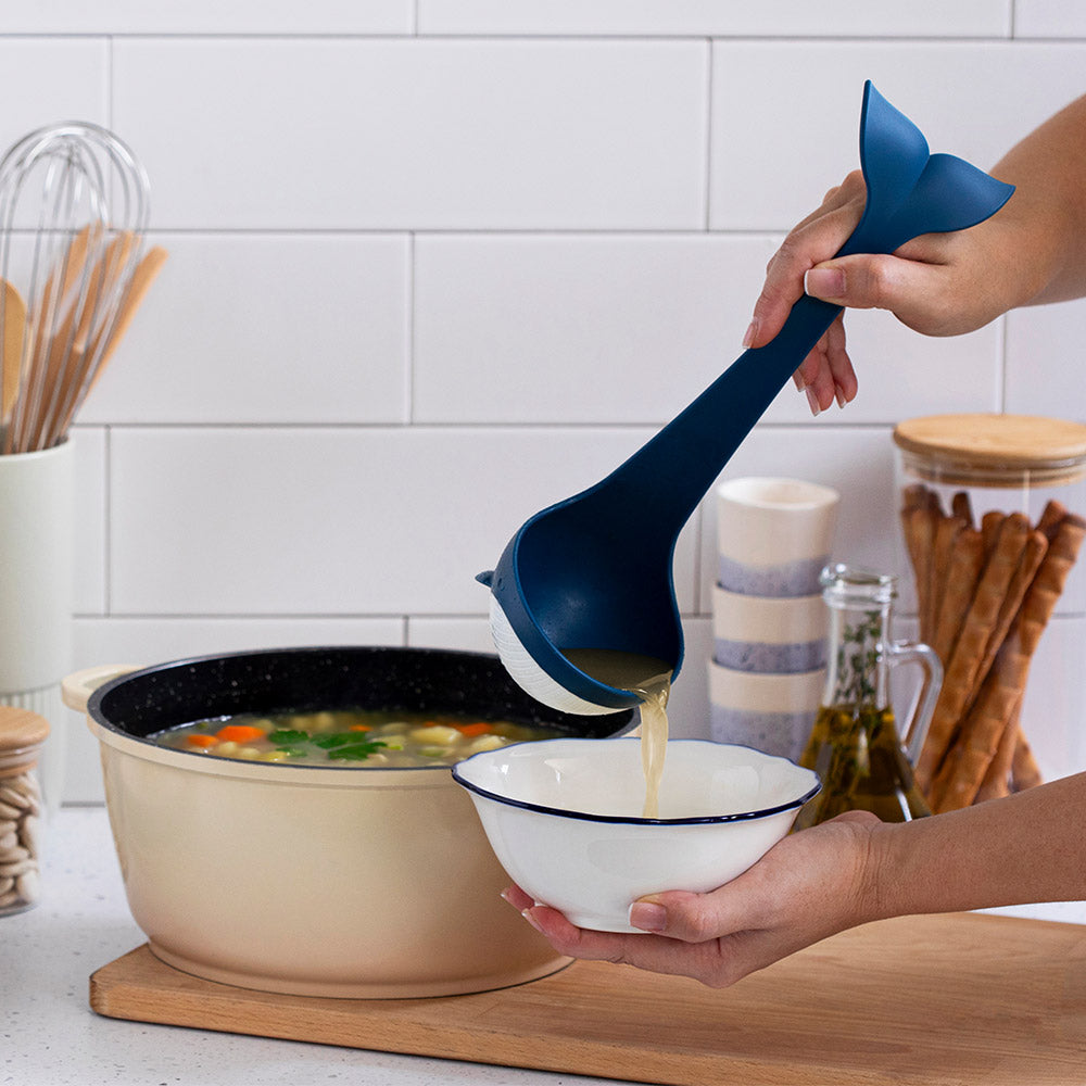 Person using the souper tail ladle to serve soup from a pot into a bowl in a kitchen setting