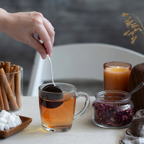Person dippin' the cookietea infuser in a glass mug