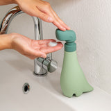 Person using the Soapasaurus soap dispenser on a sink